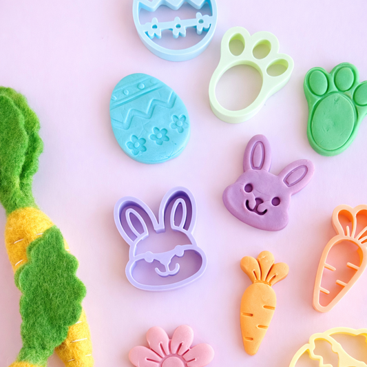 Set of colorful cookie cutters shaped like animals and objects on a pink background