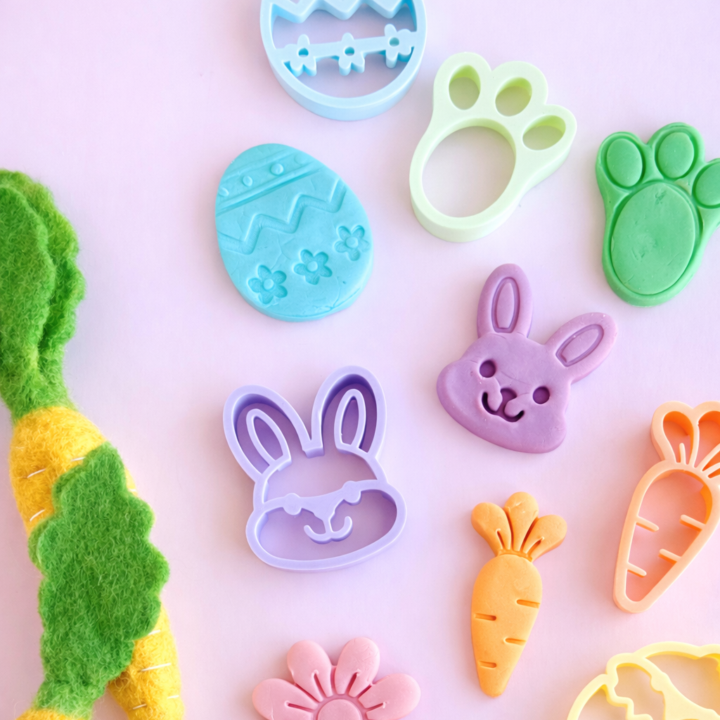 Set of colorful cookie cutters shaped like animals and objects on a pink background