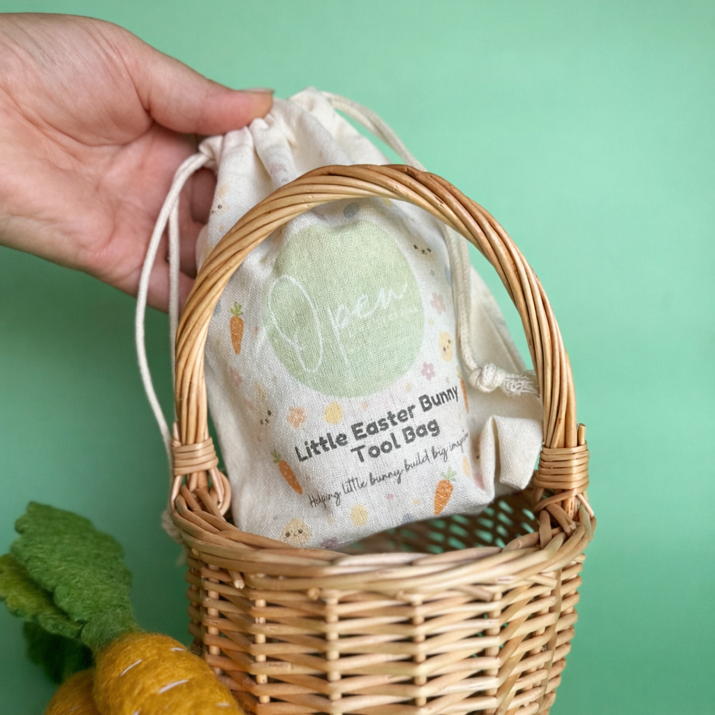 Wicker basket with a drawstring bag labeled 'Little Easter Bunny Tool Bag' on a green background.